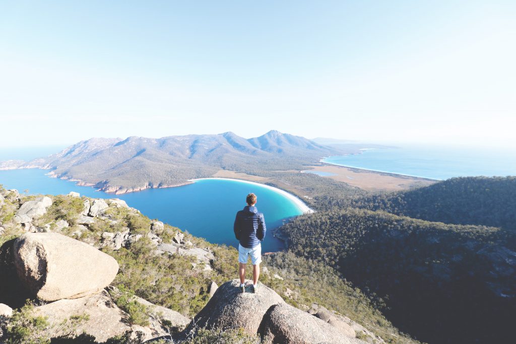 Daniel blickt von einem Berg im Freycinet Nationalpark auf die für Tasmanien berühmte Wineglass Bay Bucht.