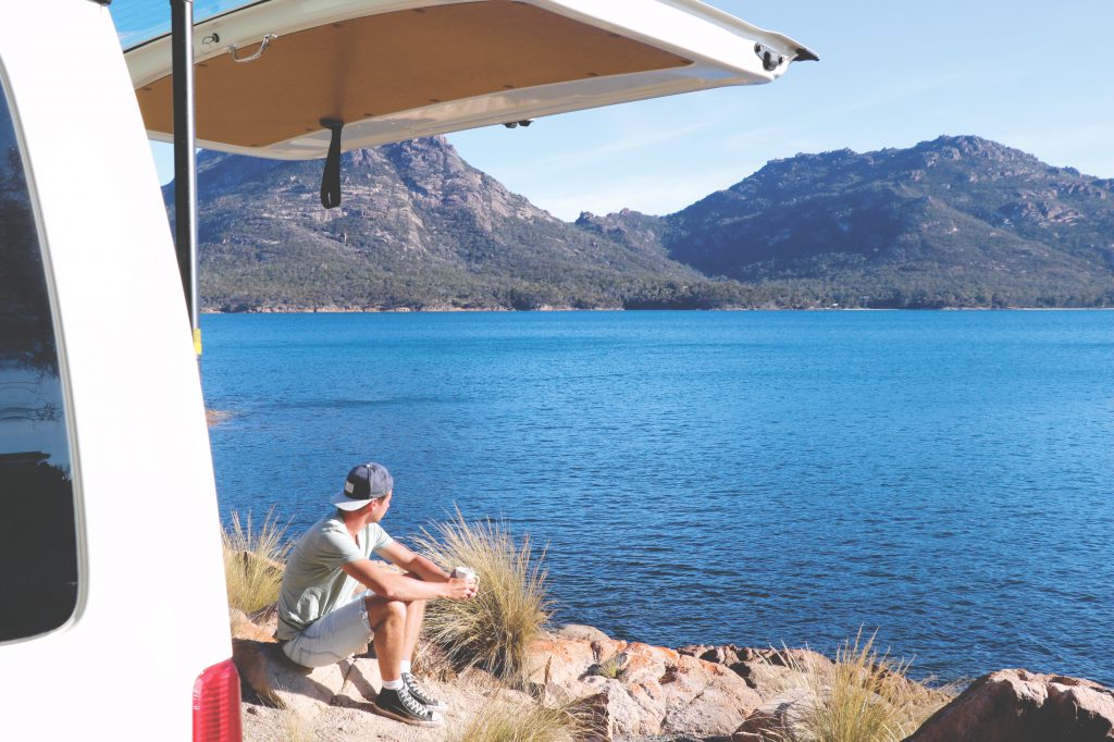 Meerblick: Daniel genießt eine Tasse Kaffee direkt am Meer. Links neben ihm der Van mit die beiden durch Tasmanien fuhren.