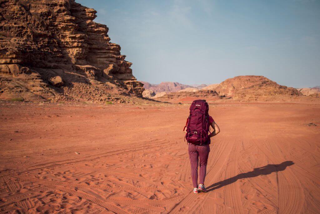 Maria mit ihrem Tatonka Yukon Trekkingrucksack in der Wüste Wadi Rum mit Blick auf die umliegenden Felsen.