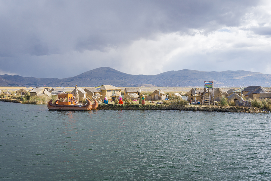 Boote und Hütten am Ufer von Puno.