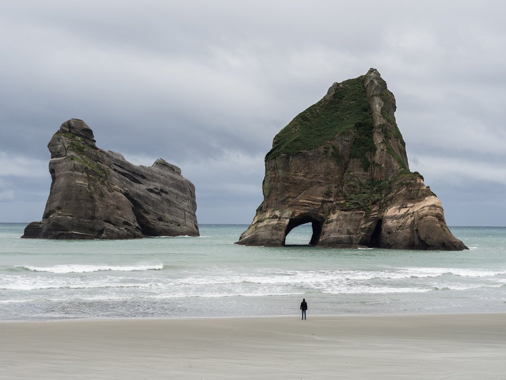 Riesige Felsen ragen am Wharariki Beach in Neuseeland aus dem Wasser.