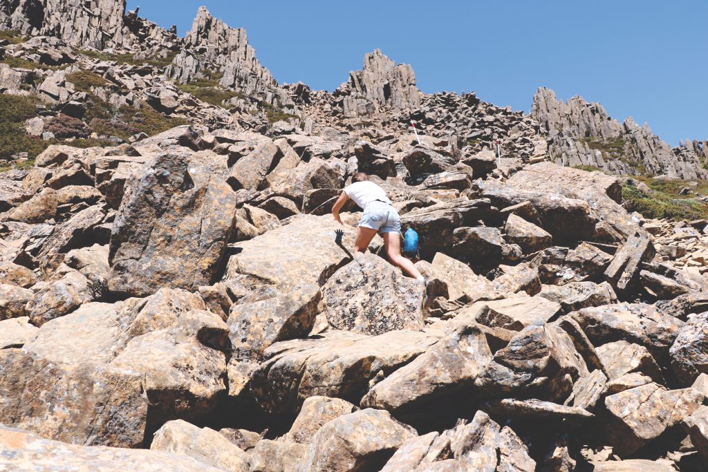 Ania zieht sich mit beiden Händen die Felsen im Cradle-Mountain-Lake-St.-Clair-Nationalpark hoch.