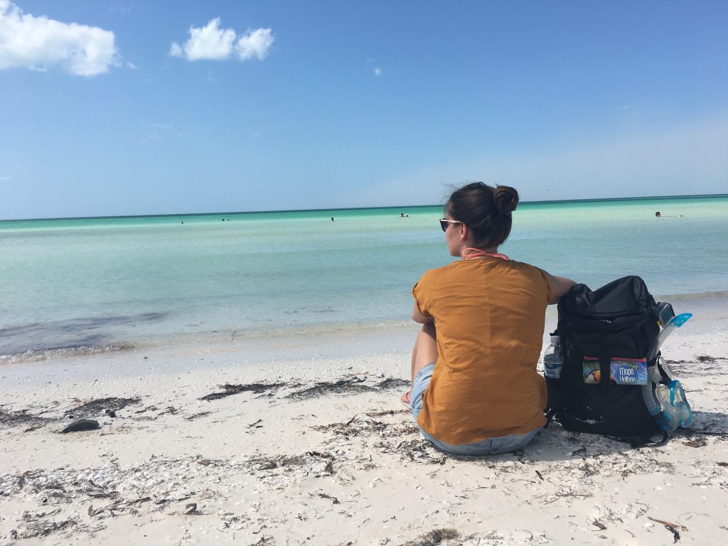 Roadtrip Yucatan - Sophie sitzt am Strand von Holbox in Mexiko und genießt das Rauschen des Meeres.