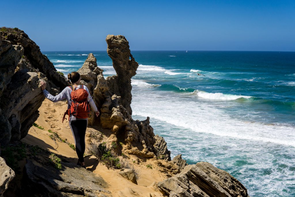 Klicken, um Bild zu vergrößern. Die Garden Route Südafrika - Sara von der Tatonka Trekkin' Crew an einer Klippe am Meer vor Südafrika.