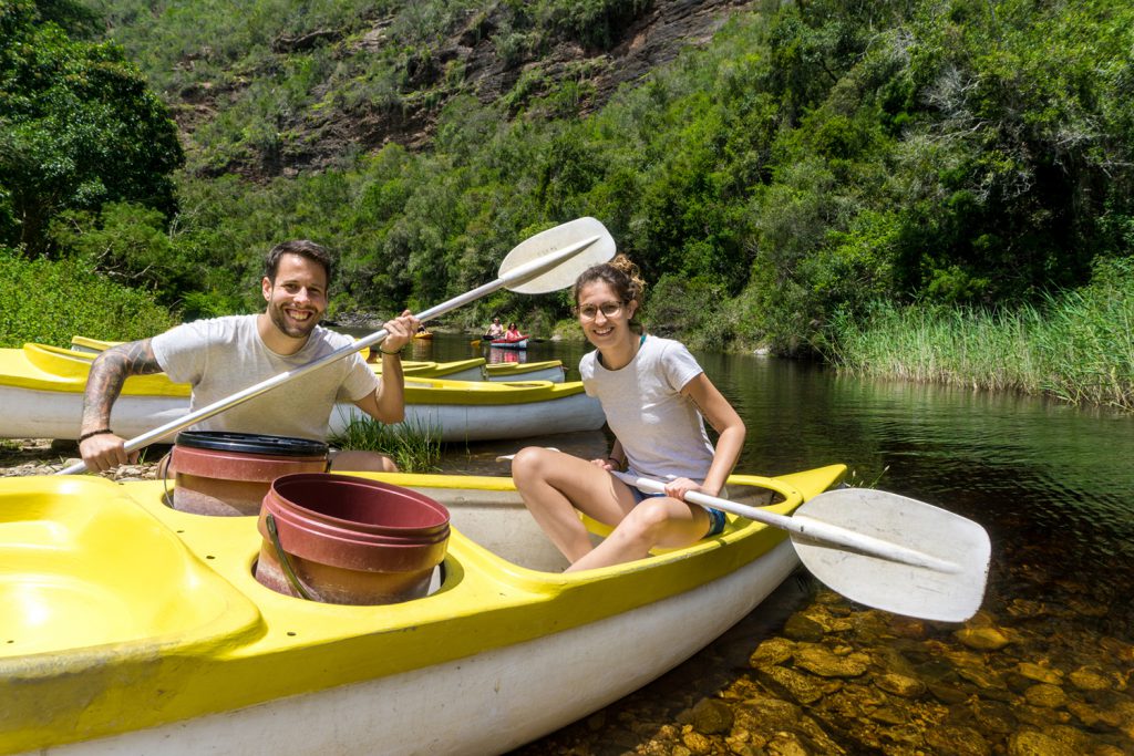 Garden Route Südafrika - Sara und Marco sitzen auf Fluss Touw in einem gelb-weissen Kanu.