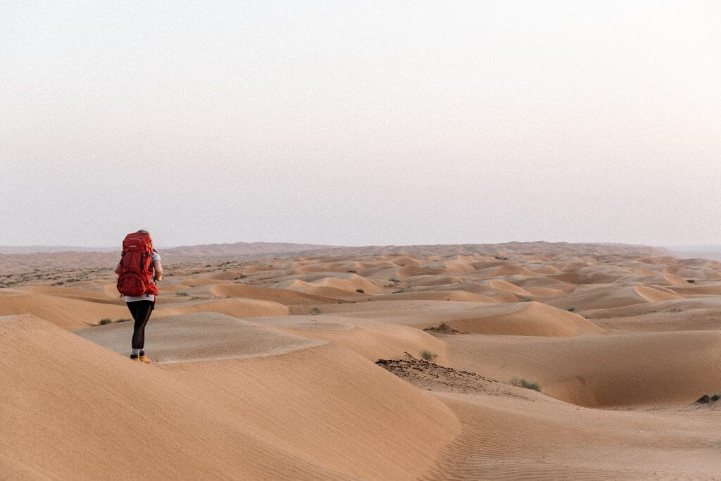 Joanna mit ihrem Tatonka Yukon Trekkingrucksack auf dem Rücken auf einer Sanddüne in der Wahiba Sands Wüste im Oman.