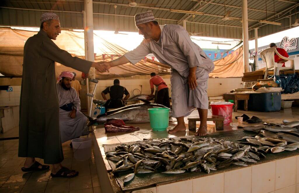 Abgeschlossenes Geschäft? Händler geben sich auf einem Fischmarkt im Oman die Hand.